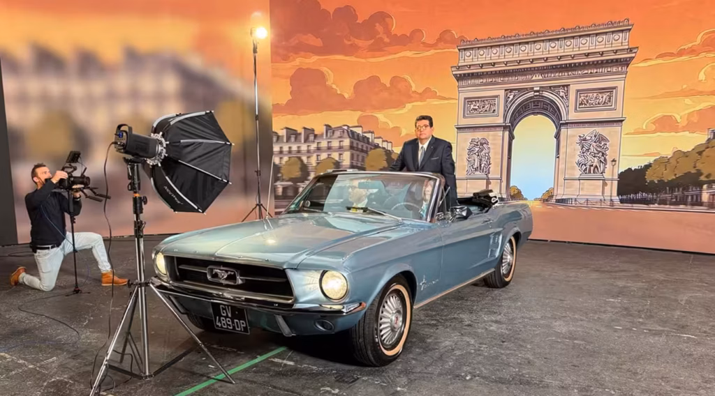 Tournage photo et vidéo au Studio Webcast avec une Ford Mustang vintage devant un fond LED illustré Arc de Triomphe, cadreur en action